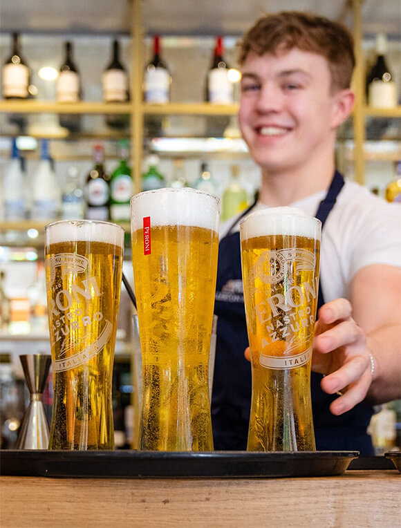 A bartender at allerton manor smiling with some beers